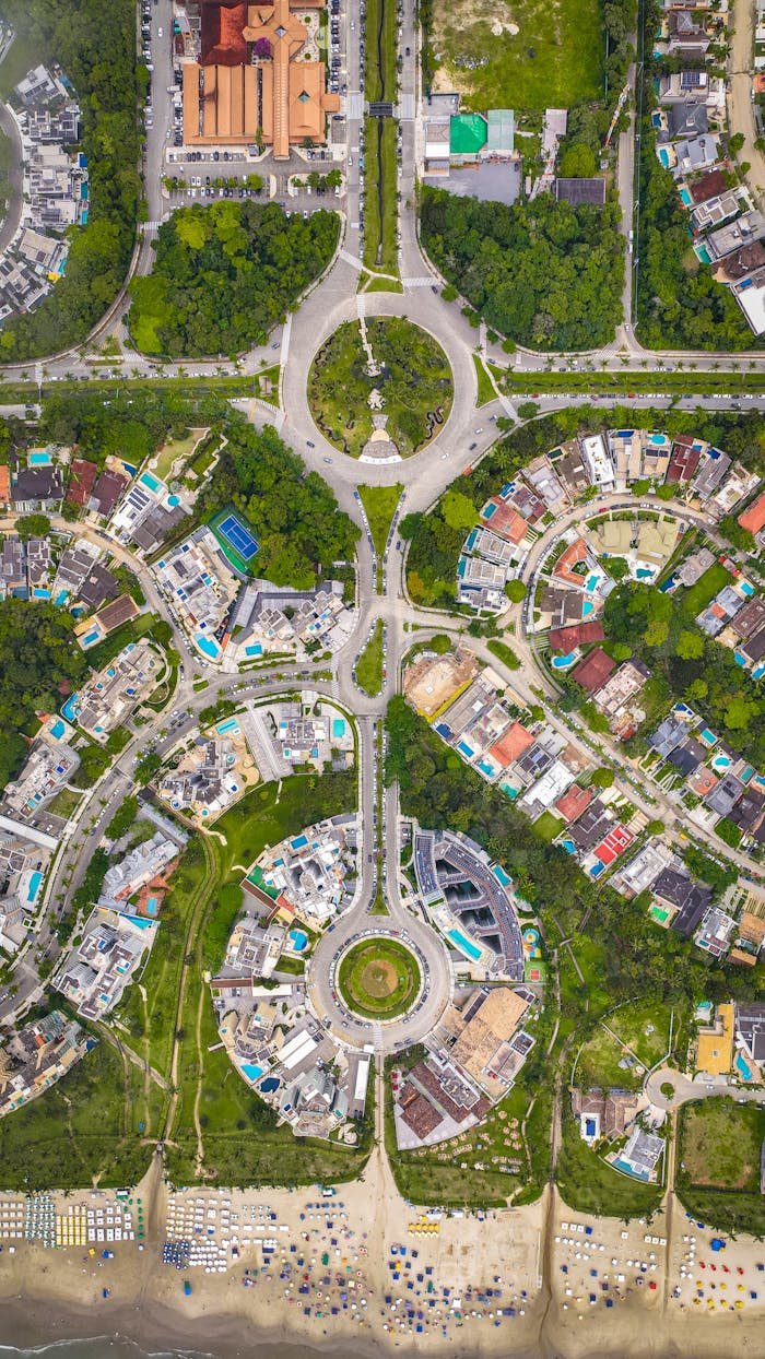 Drone image showcasing a unique circular city design beside a vibrant beachfront.